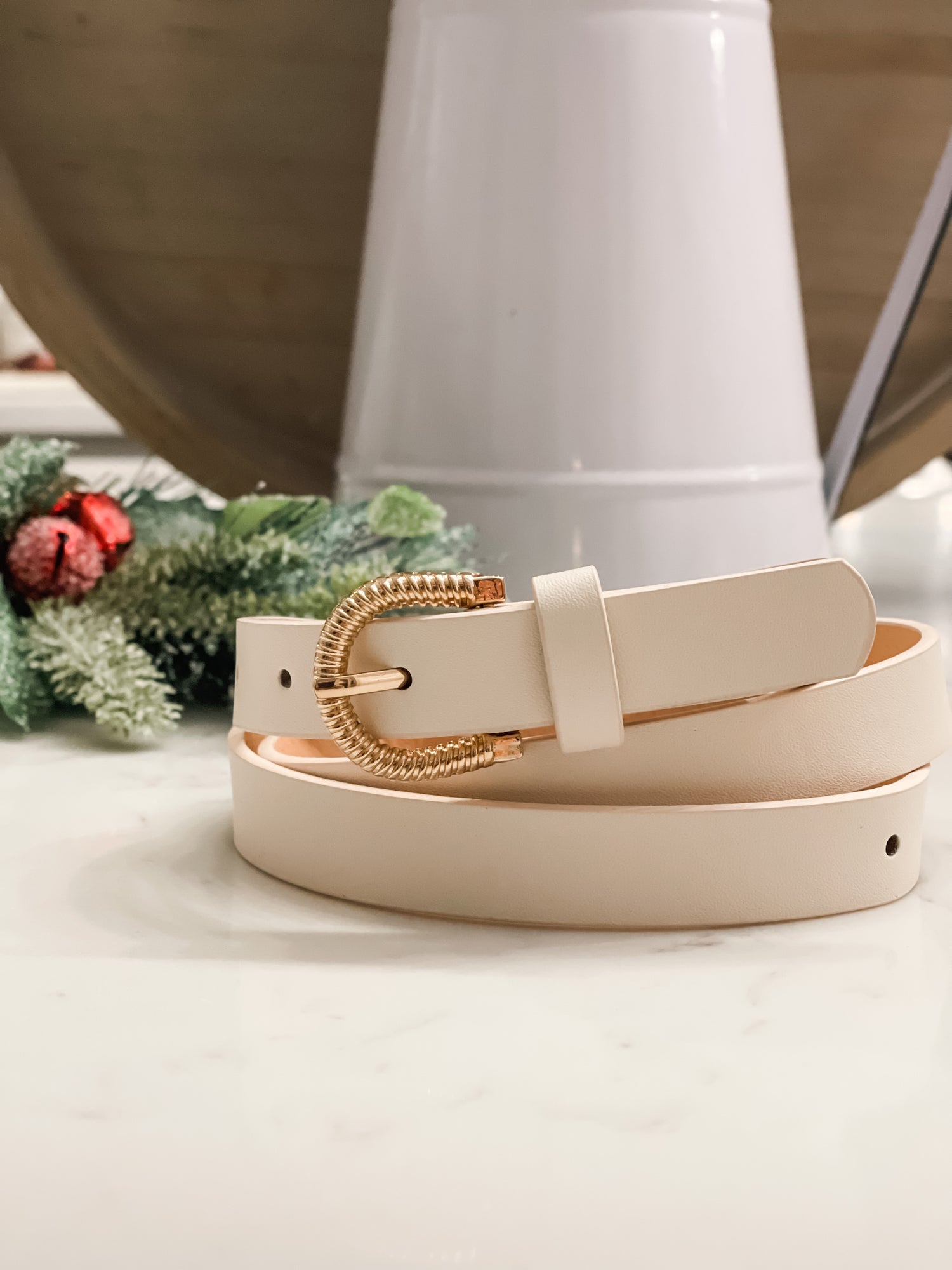 A nude colored belt with a gold belt buckle